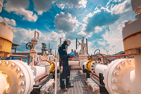 worker in safety gear inspecting equipment on gas pipeline with industrial valves and cloudy sky in the background focusing on two important maintenance tasks